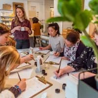 People taking a Calligraphy workshop writing on a clipboard paper holder