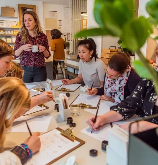 People taking a Calligraphy workshop writing on a clipboard paper holder