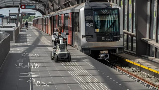 A person in an electric wheelchair riding on the metro platform.