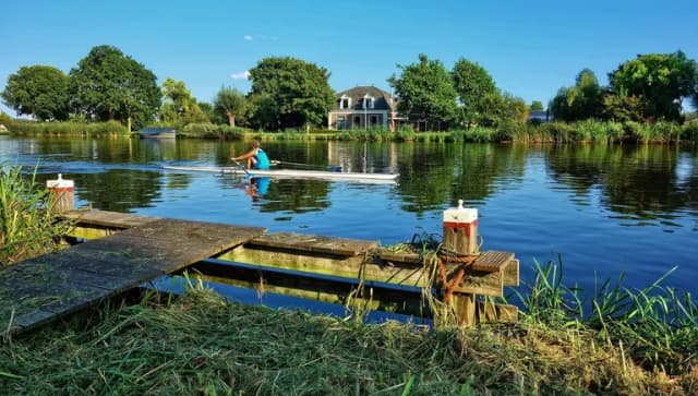 A woman in a rowboat rowing Amstelveen lake side