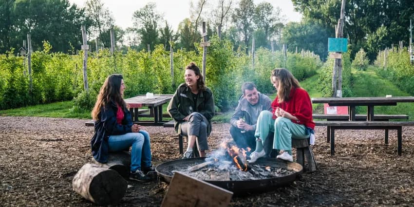 People sitting around the campfire at Fruittuin van West.
