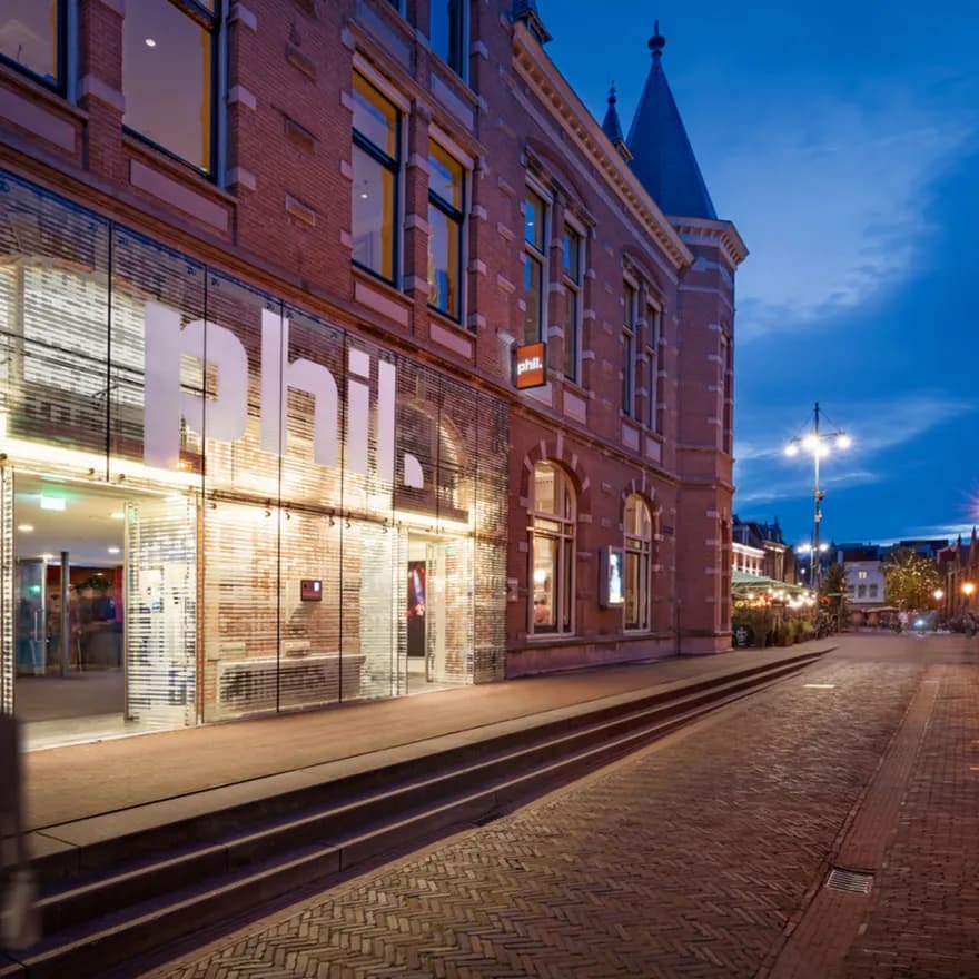 Couple walking past the exterior of PHIL Haarlem concert hall at night