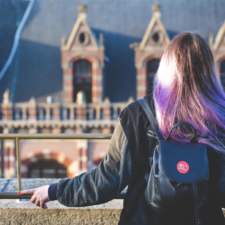 Woman standing on a rooftop with Startup sticker on bag.