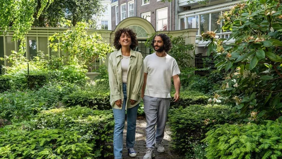 A couple walks trough the garden of Huis Marseille.