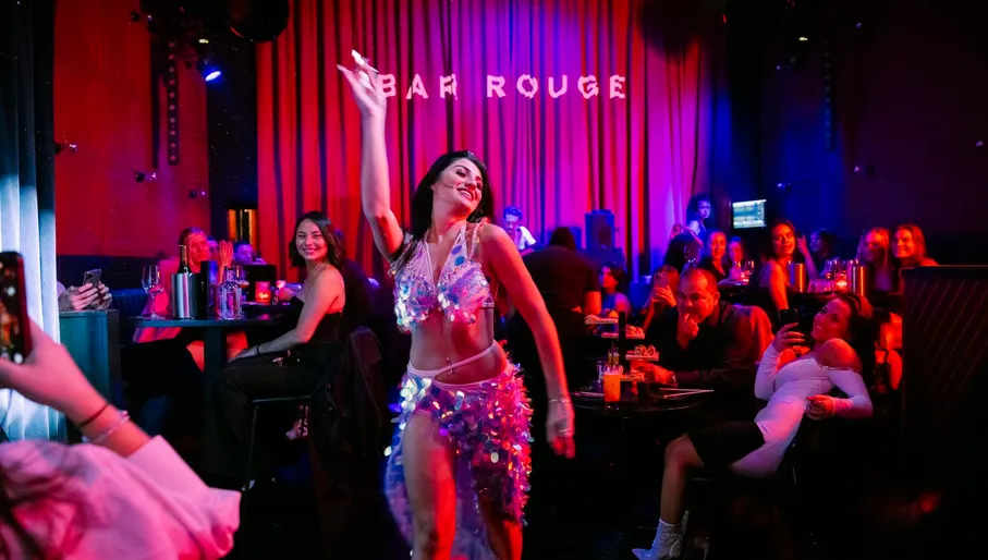 Bar Rouge, interior with drinks and people in the bar, woman giving a show dancing and people smiling