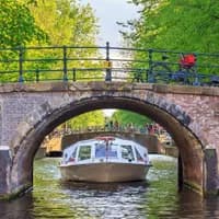 Canal cruise boat goes under the bridge over the Herengracht canal.