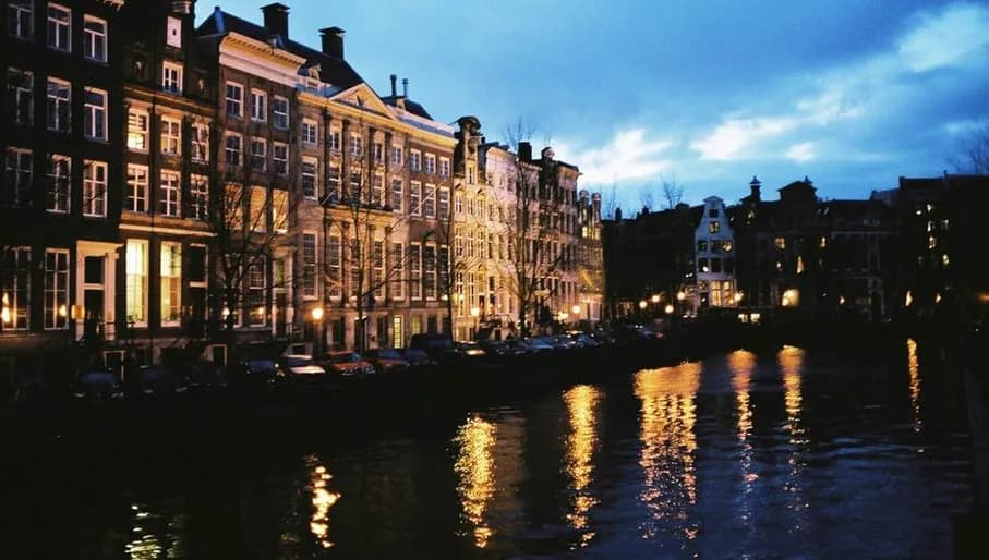 Amsterdam canal at night with reflections of lights on water