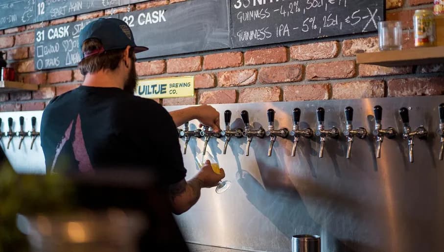 The bartender taps beer for his customers in the Uiltje Bar in Haarlem